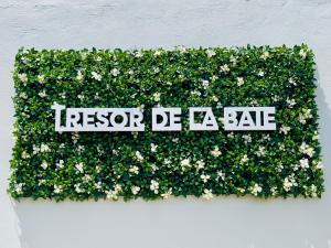 ein Zeichen in einer Blumenhedge an der Wand in der Unterkunft Sublime Villa Piscine - Trésor de la Baie in La Trinité
