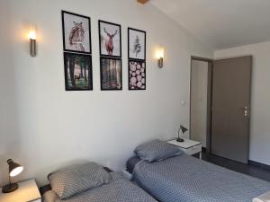 two beds in a bedroom with pictures on the wall at La Meije, Chalets Reflets de Montagne in Le Bourg-dʼOisans