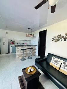 a living room with a black couch and a kitchen at Posada Lkjay Providencia Isla in Providencia