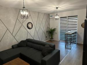 a living room with a couch and a clock on a wall at Atractiv Apartaments in Chiajna