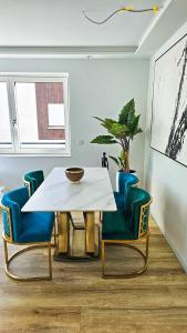 un comedor con una mesa blanca y sillas azules en Luxus Neubau 65m2 City Wohnung - L, en Múnich