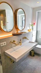 baño con lavabo y 2 espejos en Luxus Neubau 65m2 City Wohnung - L, en Múnich