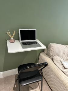 a laptop computer sitting on a white desk next to a couch at Modern En-Suite Rooms Town Centre Self-Check In in Barnsley