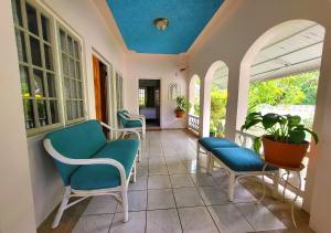 a porch with chairs and a blue ceiling at Green's Palace Jamaica in Oracabessa