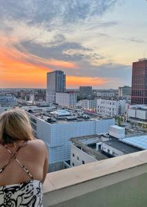 a woman standing on a ledge looking out over a city at Łódź Manhattan Aparts -Ulica Piotrkowska in Łódź