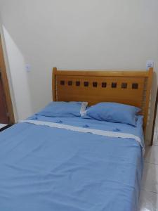 a bed with blue sheets and blue pillows at Casa de férias in Conceição da Barra