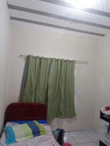 a bedroom with a bed and a green curtain at Casa de férias in Conceição da Barra