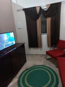 a living room with a television and a green rug at Casa de férias in Conceição da Barra