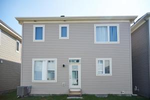 a gray house with white windows and a door at Fully Furnished En-Suite Basement in Ottawa