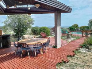 una terraza de madera con mesa y sillas. en Villa avec une piscine privée, en Quarante