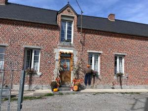 Ein Mann steht vor einem Backsteingebäude mit einer Tür. in der Unterkunft Le Terrier, chambre d'hôte à thème Le sorcier à lunettes 