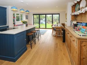 Frosthill Cottage في نيوبورت: مطبخ مع دواليب زرقاء وطاولة مع كراسي