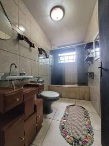 a bathroom with a toilet and a sink and a tub at Quarto em casa a 1.4km da UFSM in Santa Maria