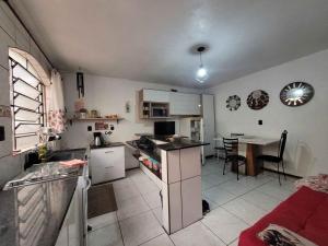 een keuken en een woonkamer met een tafel, een keuken en een eetkamer bij Quarto em casa a 1.4km da UFSM in Santa Maria