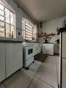 a kitchen with white appliances and a large window at Quarto em casa a 1.4km da UFSM in Santa Maria