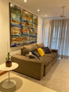 un divano marrone in soggiorno con un dipinto di Aconchegante & charmoso a Rio de Janeiro