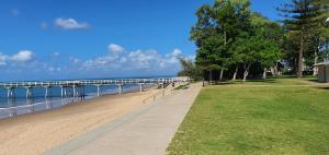 a walkway next to a beach with a pier at Villa Venezia Apt 3 - Spacious Hervey Bay esplanade apartment in Hervey Bay