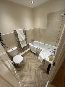 a bathroom with a toilet and a tub and a sink at Charming 2-Bed Apartment in Danbury essex in Chelmsford
