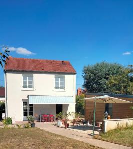 ein weißes Haus mit einem Tisch und einem Regenschirm in der Unterkunft Maison Cosne sur Loire in Cosne-Cours-sur-Loire