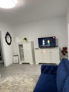 a living room with a blue couch and a flat screen tv at Escape Aparthotel in Suceava