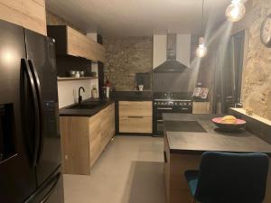 eine Küche mit einem schwarzen Kühlschrank und einer Theke in der Unterkunft Luxurious family house with pool in Ardèche. in Les Vans