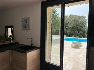 eine Küche mit einer Glasschiebetür, die zum Pool führt in der Unterkunft Luxurious family house with pool in Ardèche. in Les Vans