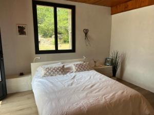 Schlafzimmer mit einem großen weißen Bett und einem Fenster in der Unterkunft Luxurious family house with pool in Ardèche. in Les Vans
