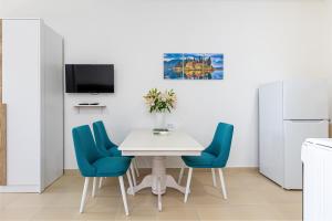 una cucina con un tavolo bianco e sedie blu di Apartments Lustica a Tivat
