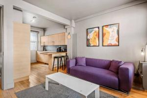 a living room with a purple couch and a kitchen at Spacious Home on Chapel Market in London