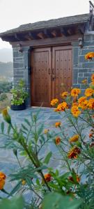 a building with a wooden door and a bunch of flowers at Point of view 2 in Pramanta