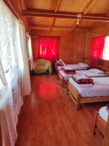Habitación con 3 camas y cortinas rojas. en Alma Patagona Hostel, en Puerto Tranquilo
