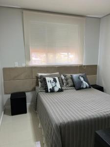 a bedroom with a large bed with a window at Apartamento JURERE in Florianópolis