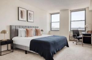 a bedroom with a bed and a desk and two windows at The Urban Retreat 3BR Apartment in NYC! in New York