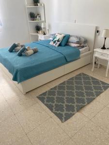 a bedroom with a bed with blue sheets and a rug at Modern Apartment in Pafos Near the Sea in Paphos