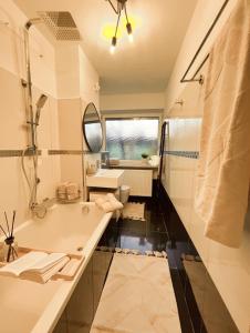 a bathroom with a tub and a sink and a mirror at Stilvolle 3-Zimmer Wohnung in Ingolstadt mit Balkon und guter Autobahnanbindung in Ingolstadt
