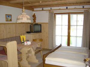 um quarto com uma cama, uma mesa e uma televisão em Ferienwohnungen Almbrünnerl - Chiemgau Karte em Inzell