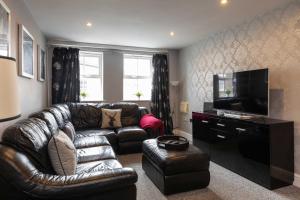 a living room with a leather couch and a flat screen tv at Regent House in Thirsk