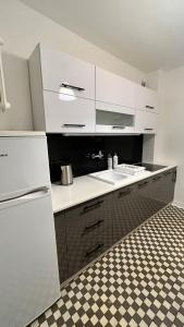 a kitchen with white cabinets and a checkered floor at Warszawa Krucza Pokoje in Warsaw