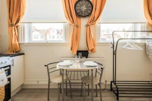 a dining room with a table and chairs and a clock on the wall at Clacton Stays, Seaside Central location in Clacton-on-Sea