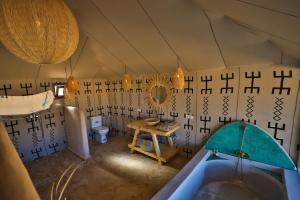 a room with a tub and a table in a tent at Aiour Luxury Camp in Merzouga