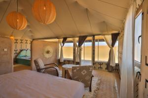 a room with a bed and a table and chairs at Aiour Luxury Camp in Merzouga