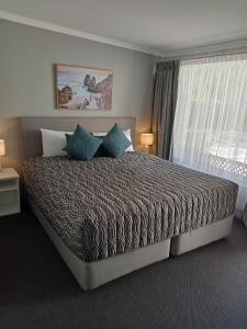 卧龙岗Solomon Inn Motel Figtree的卧室里有一张大床，配有蓝色枕头