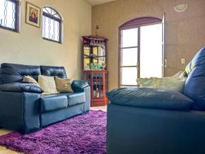 a living room with two blue leather couches and a purple rug at Otima casa de campo com churrasq em Sorocaba SP in Sorocaba