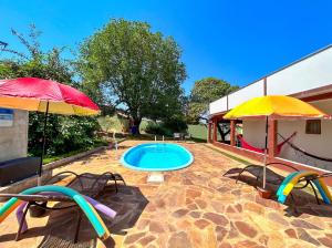 a patio with a pool and two umbrellas and a swimming pool at Otima casa de campo com churrasq em Sorocaba SP in Sorocaba