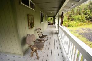 un porche de una casa verde con 2 sillas en Private House Located between Volcano and Hilo en Mountain View