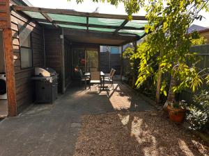 un patio con mesa y sillas bajo una pérgola en Glenelg House en Adelaida