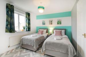2 camas en un dormitorio con paredes azules y blancas en Detached house with BIG monthly discount!, en Peterborough