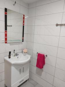 a white bathroom with a sink and a mirror at Apartman Riki in Sarajevo
