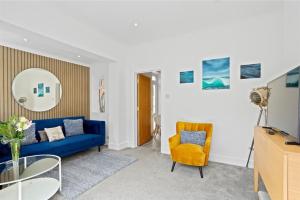 a living room with a blue couch and a yellow chair at Captain's Quarters in Hythe