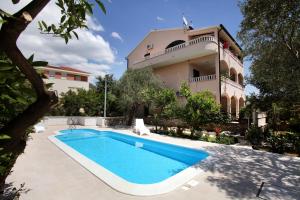 a villa with a swimming pool in front of a house at Villa Sun in Seget Vranjica